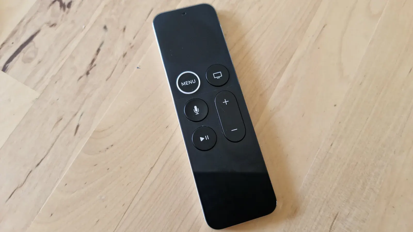 Apple TV remote control resting on a wooden table