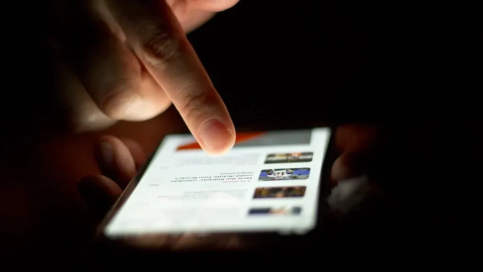 Close-up of a hand scrolling through a news app on a smartphone
