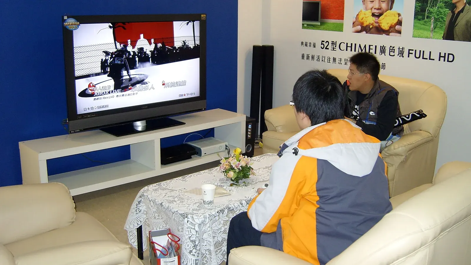 Two people sitting on a couch watching a game on a television